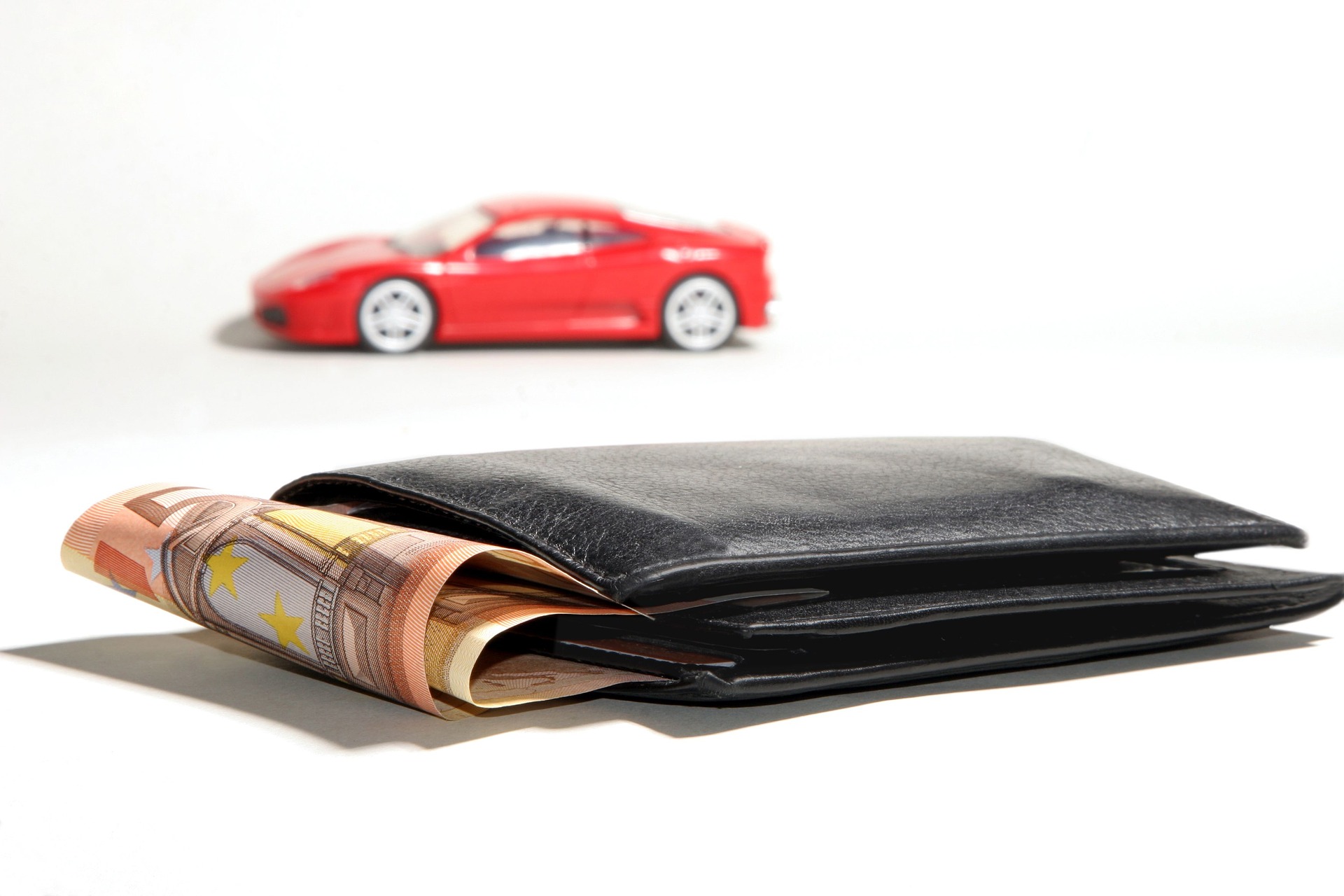 Wallet with money and car in the background